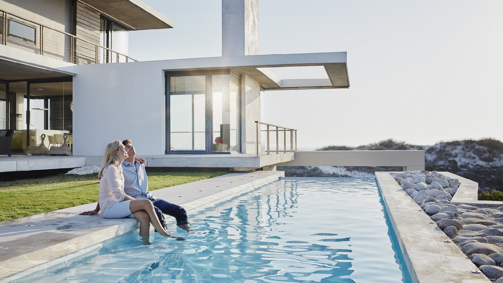 Relaxed couple sitting together at pool in backyard
